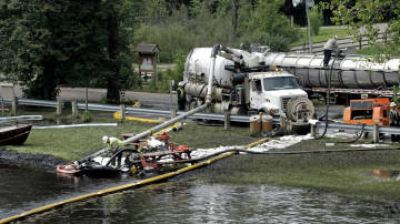 Workers using suction hoses try to clean up an oil spill this week from the Kalamazoo River in Battle Creek, Mich.